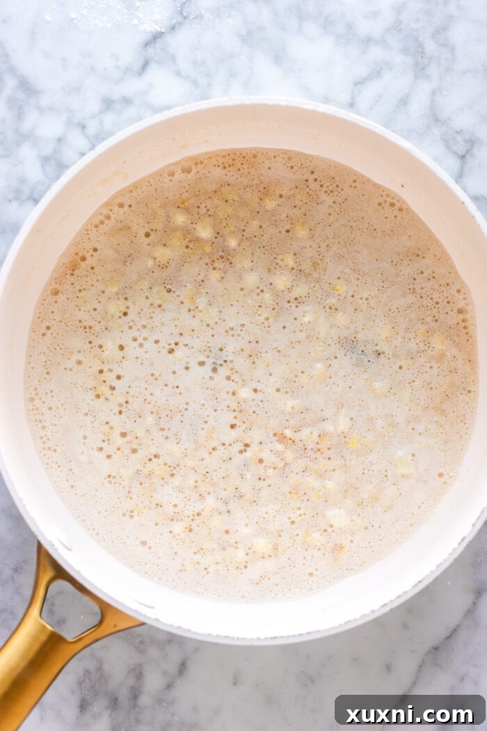 Minced garlic being sautéed in brown butter in a pan until lightly golden and fragrant.