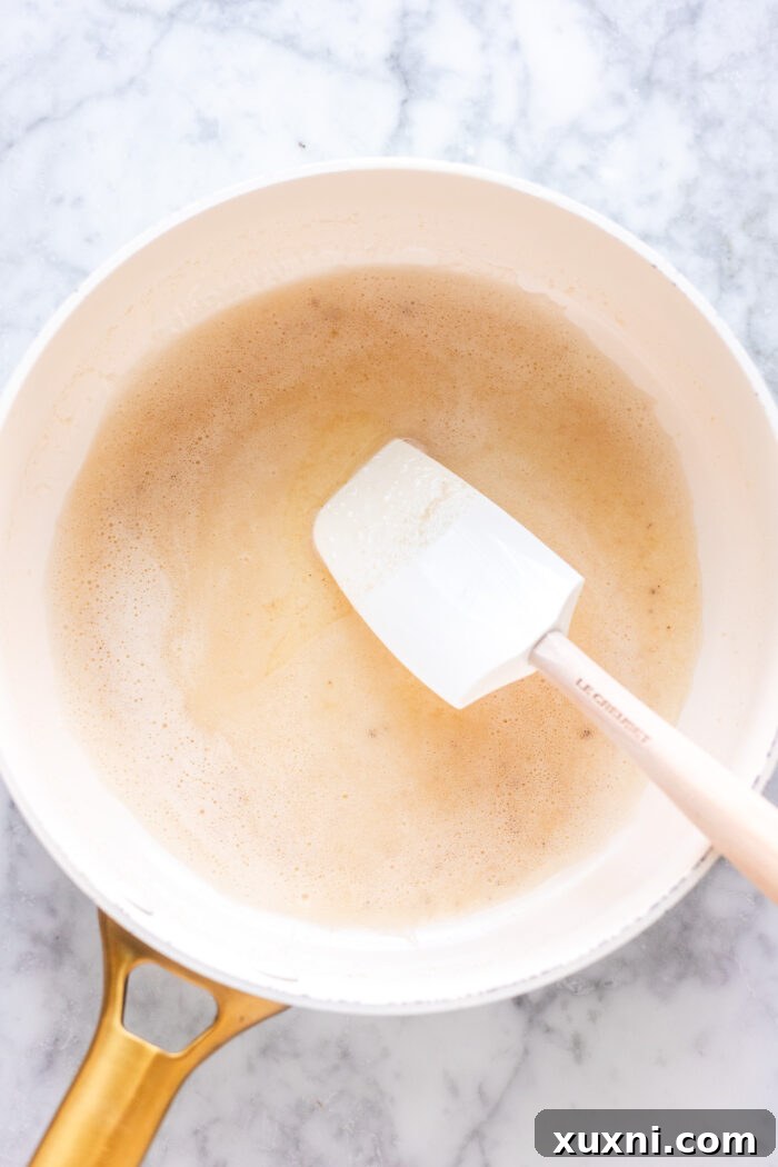 Vegan butter melting and beginning to brown in a sauté pan, showing light brown flecks.