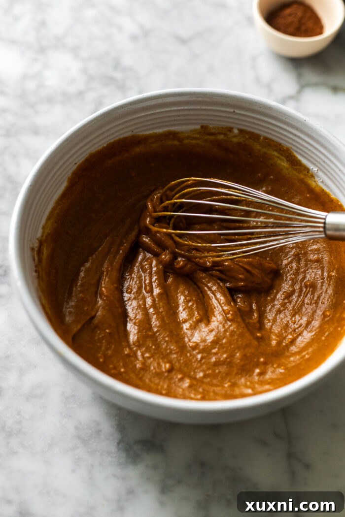 Step-by-step image of whisking the pumpkin cream ingredients together in a bowl, showcasing the vibrant orange color and smooth texture.