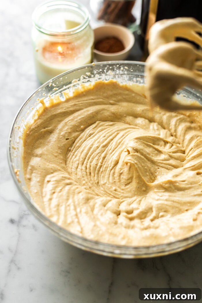 Combining the rich pumpkin cream and the fluffy mascarpone cream to form the final, harmonious pumpkin mascarpone filling, showing the gentle folding technique.