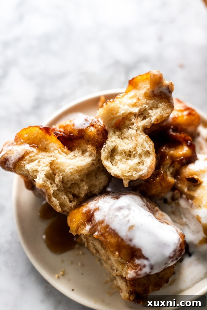 A close-up shot of a sticky toffee monkey bread, pulled apart to reveal its soft, gooey interior and the rich date and cinnamon coating
