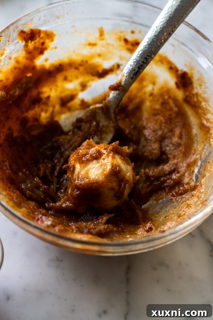 A small monkey bread dough ball being dipped into rich date puree