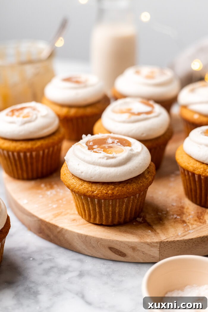 Two beautifully frosted vegan caramel cupcakes, adorned with a final drizzle of caramel and flaky sea salt, ready to be served.