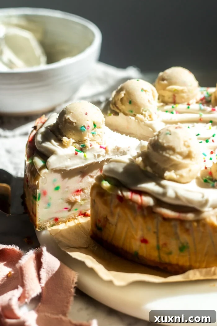 Sliced vegan sugar cookie dough cheesecake revealing its layered shortbread crust, creamy vanilla sprinkle filling, and festive cookie dough balls.