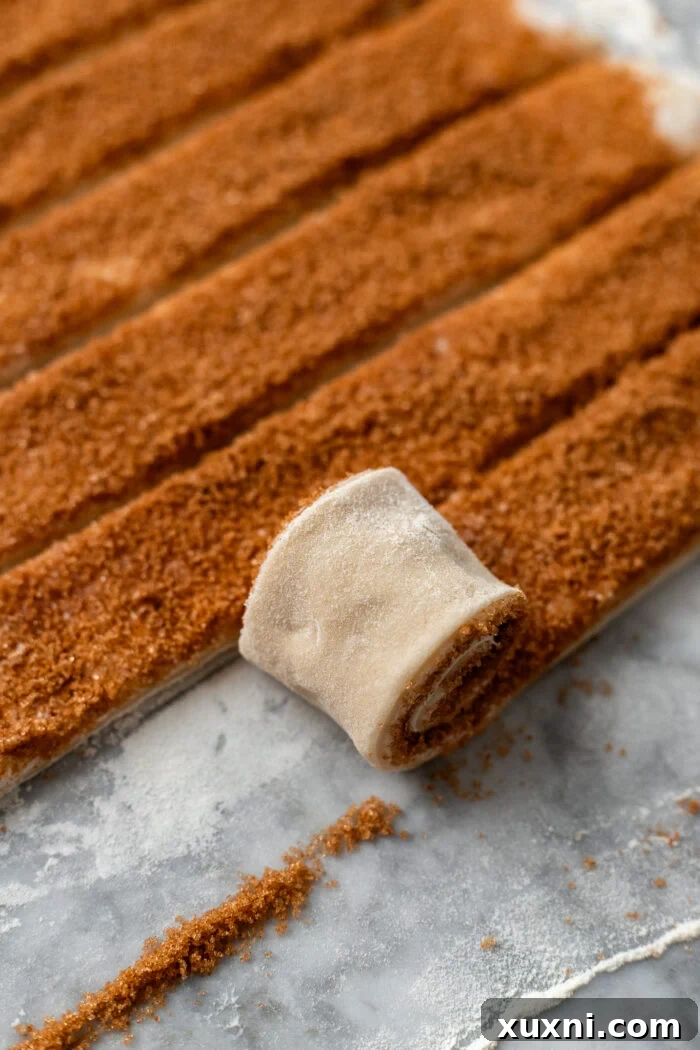 Rolling the filled vegan cinnamon roll dough into a tight log.