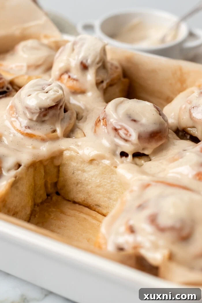 Vegan cinnamon rolls in a casserole dish, glistening with frosting and ready to be served.