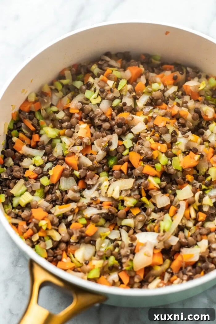 The Easiest 8-Ingredient Plant-Based Bolognese 5 Finely chopped onions, carrots, and celery sautéing in a pan with olive oil, creating an aromatic base for the bolognese.