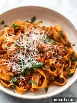 The Easiest 8-Ingredient Plant-Based Bolognese 10 Perfect bowl of lentil bolognese with grated vegan parmesan on top, ready to be served.
