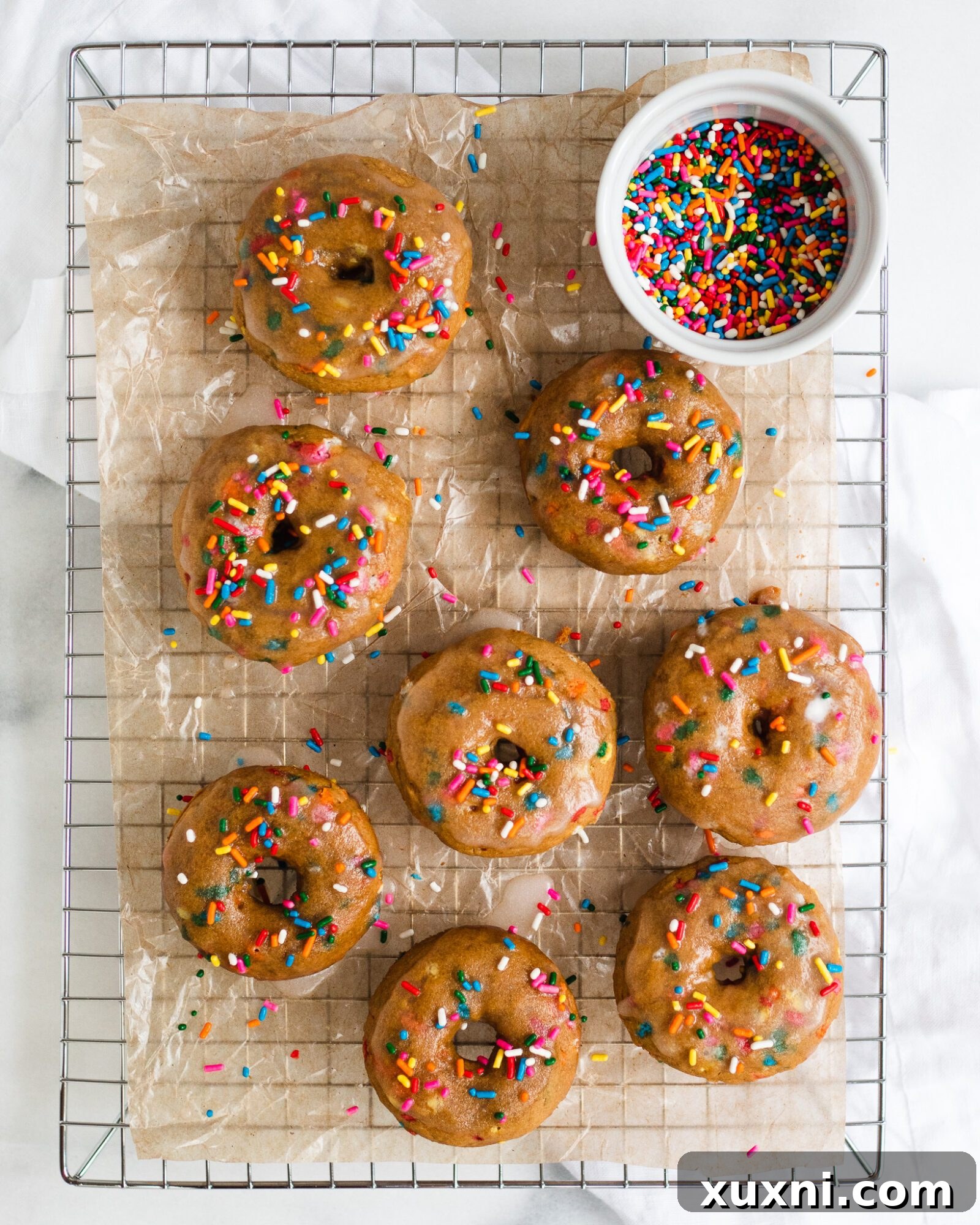 Vegan Birthday Donut Delights 10 baked donuts on drying rack with sprinkles