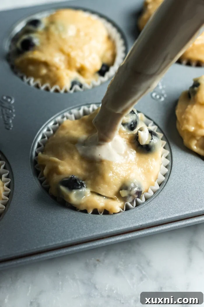 filling the lemon blueberry muffins with cream cheese