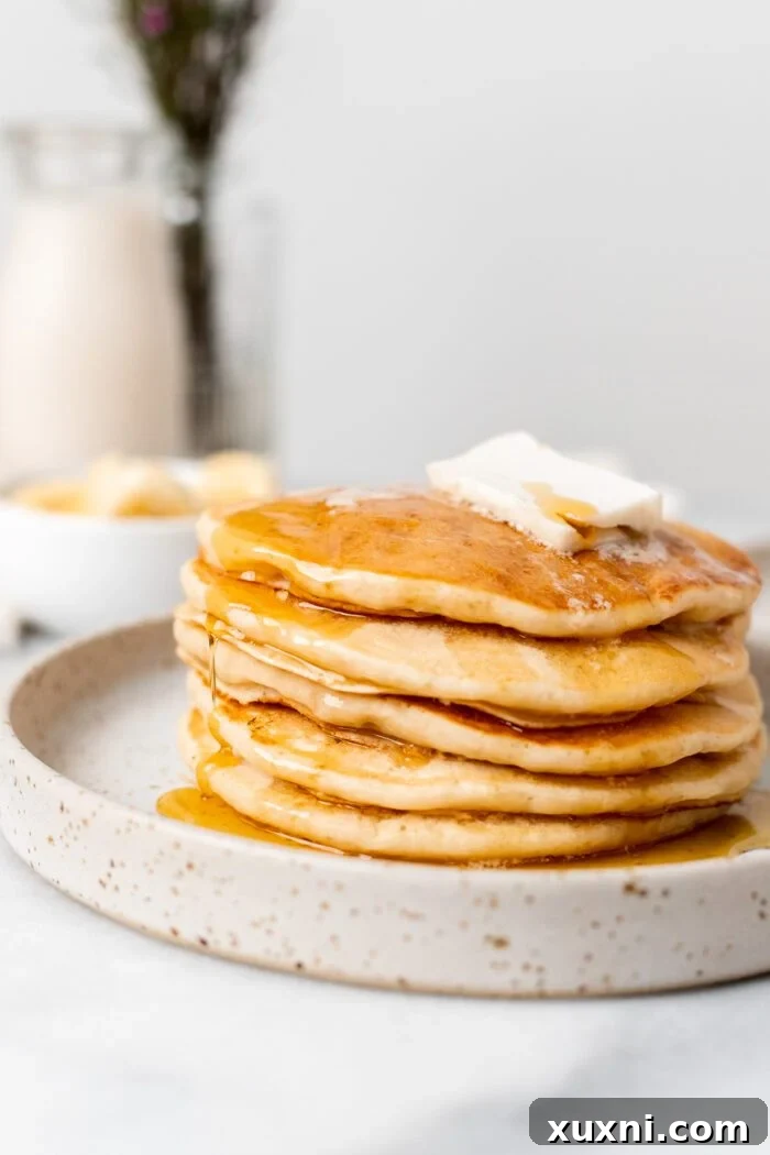 Stack of ultra fluffy vegan pancakes drizzled with maple syrup