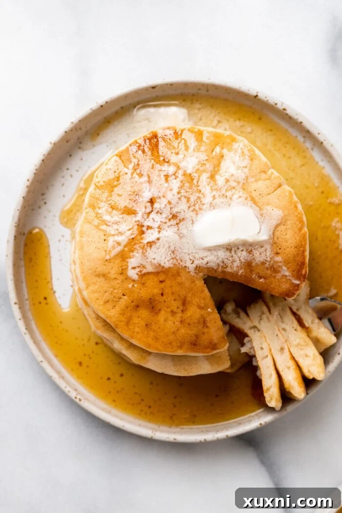 Close-up of a stack of fluffy vegan pancakes, revealing their airy interior when sliced