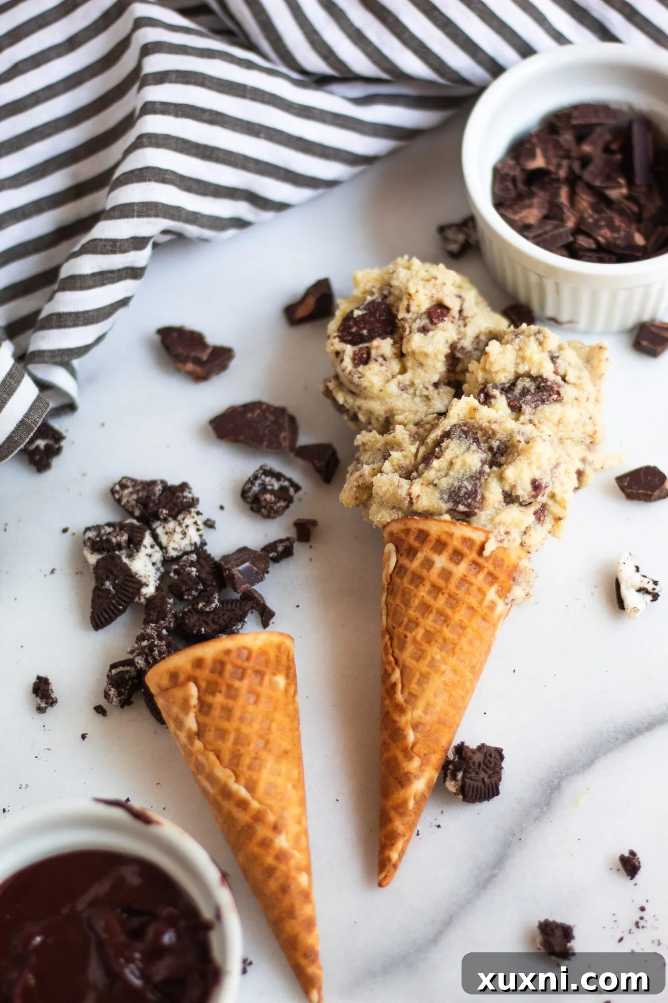 oreo cookie crumbles falling out of ice cream cone on marble slab