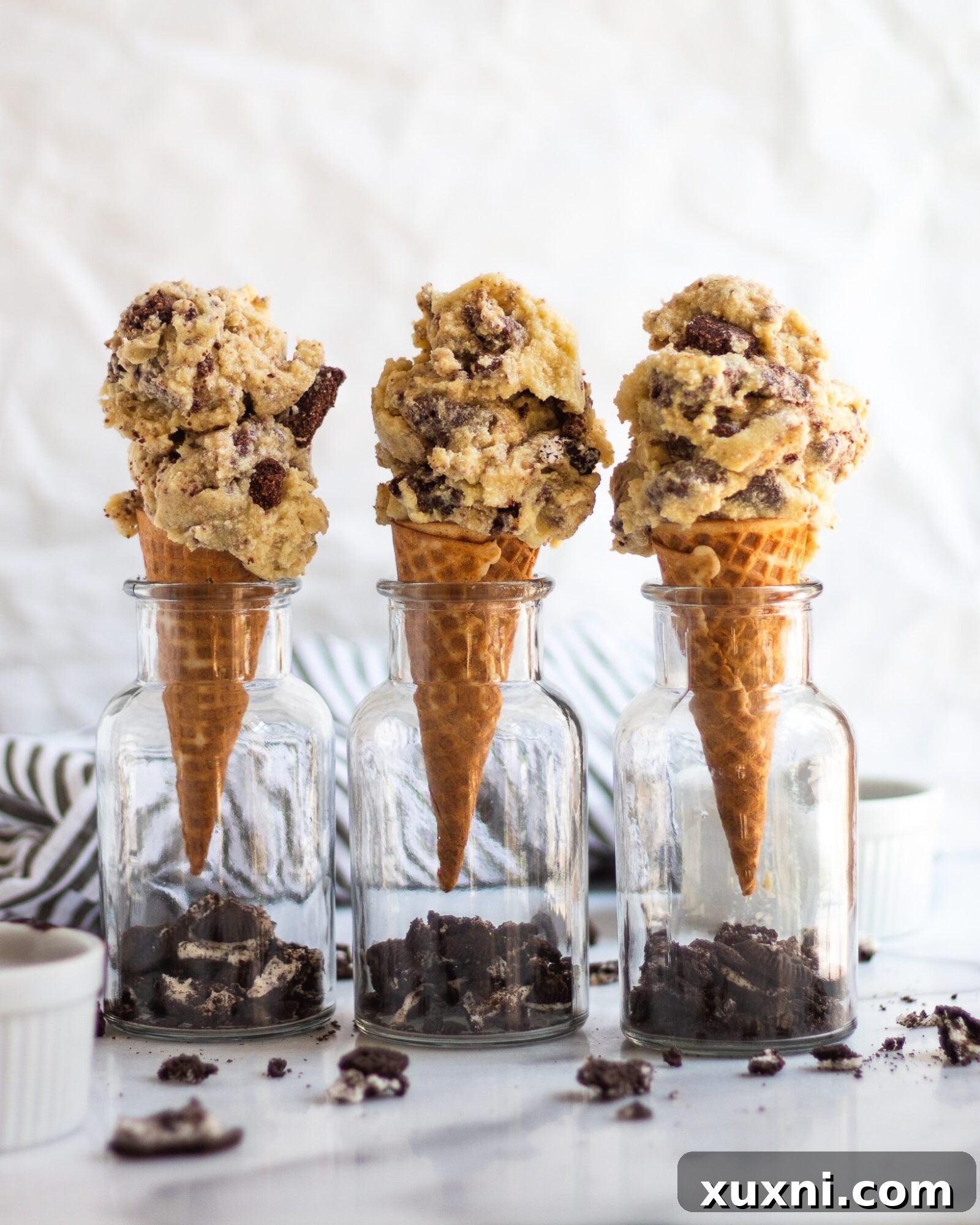 three ice cream cones with scoops of cookies and cream ice cream