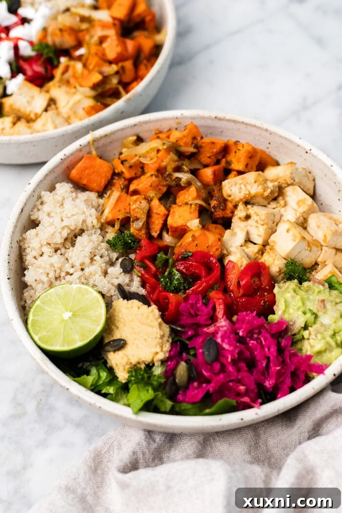 Two generously portioned roasted sweet potato tofu bowls on a sleek marble table, showcasing the colorful ingredients.