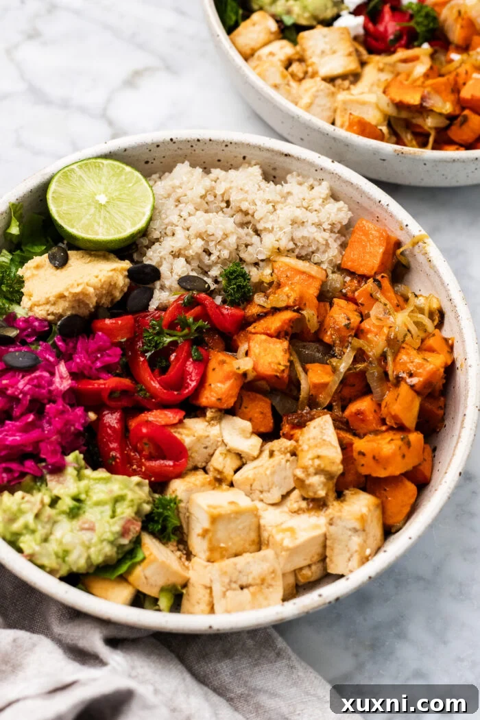 A close-up of a crispy sweet potato tofu bowl, garnished with fresh herbs, on a wooden table.