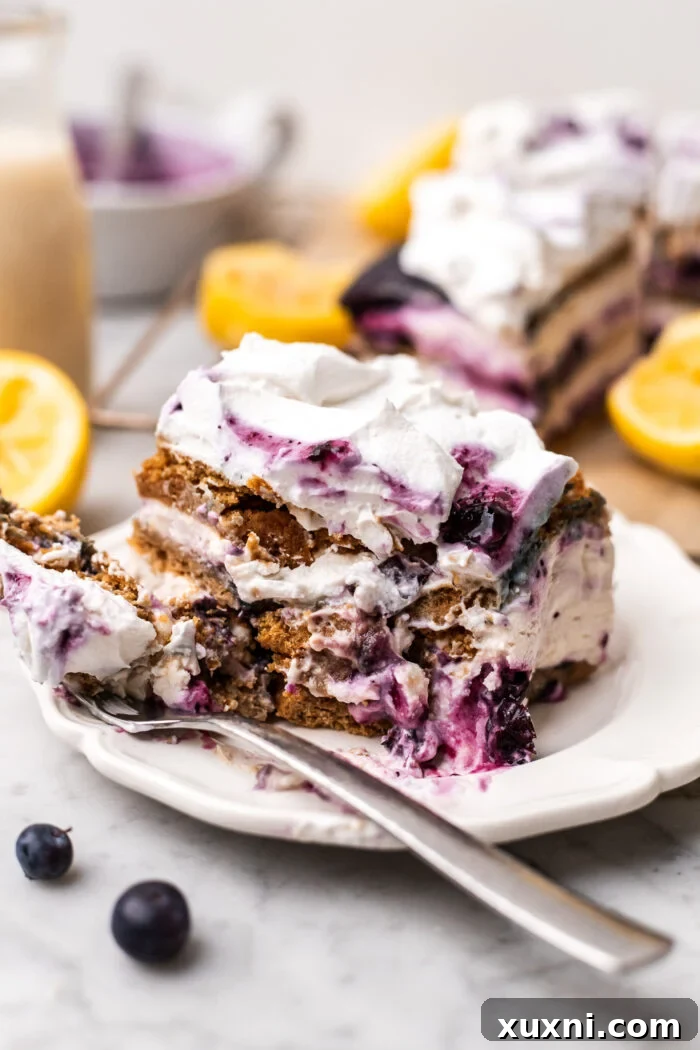 A slice of vegan lemon blueberry icebox cake with a bite taken out, showing its creamy texture.