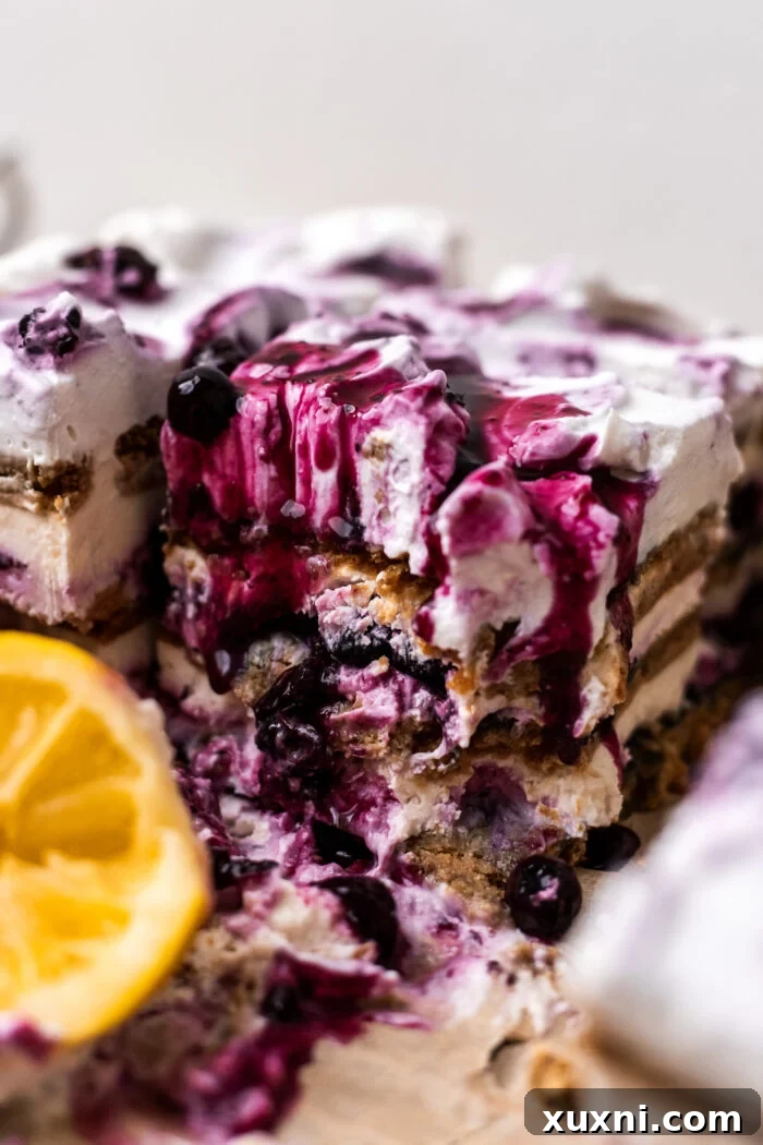 A close-up of a bitten slice of vegan lemon blueberry icebox cake, highlighting its creamy layers.