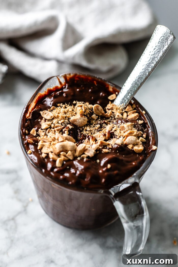 A jar filled with the prepared peanut crunch coating, a mix of vegan chocolate ganache and finely chopped salted peanuts.