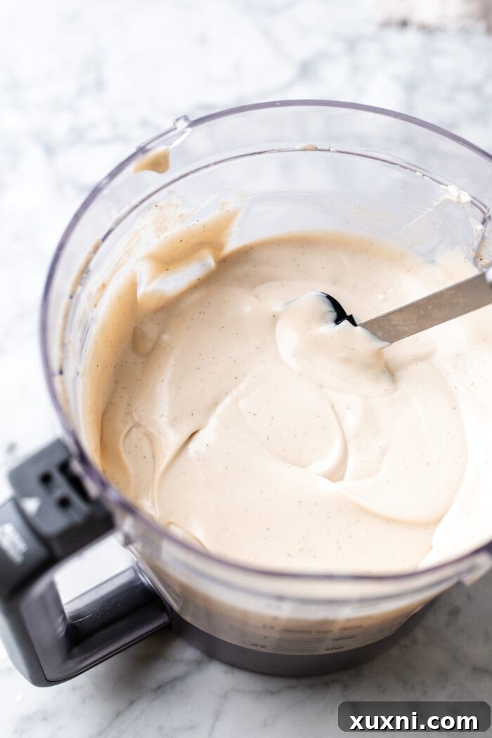 Smooth vegan vanilla cheesecake batter being blended in a food processor, ready for assembly.