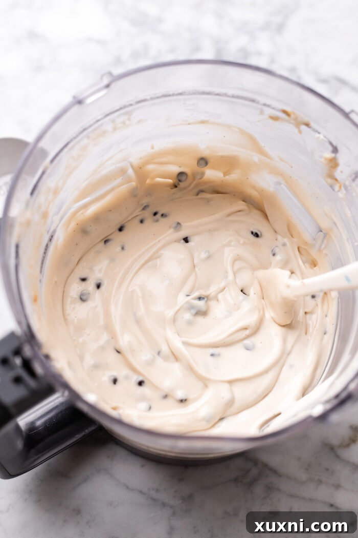 Plant-Powered Brookie Basque Cheesecake Bars for Small Cravings 6 Creamy vegan cheesecake batter being blended in a food processor.