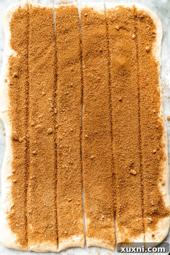 Dough spread with cinnamon sugar mixture, neatly sliced into six long strips with a pizza cutter.