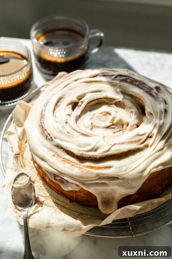The giant vegan cinnamon roll cake generously covered with maple brown butter cream cheese frosting, ready to be served.