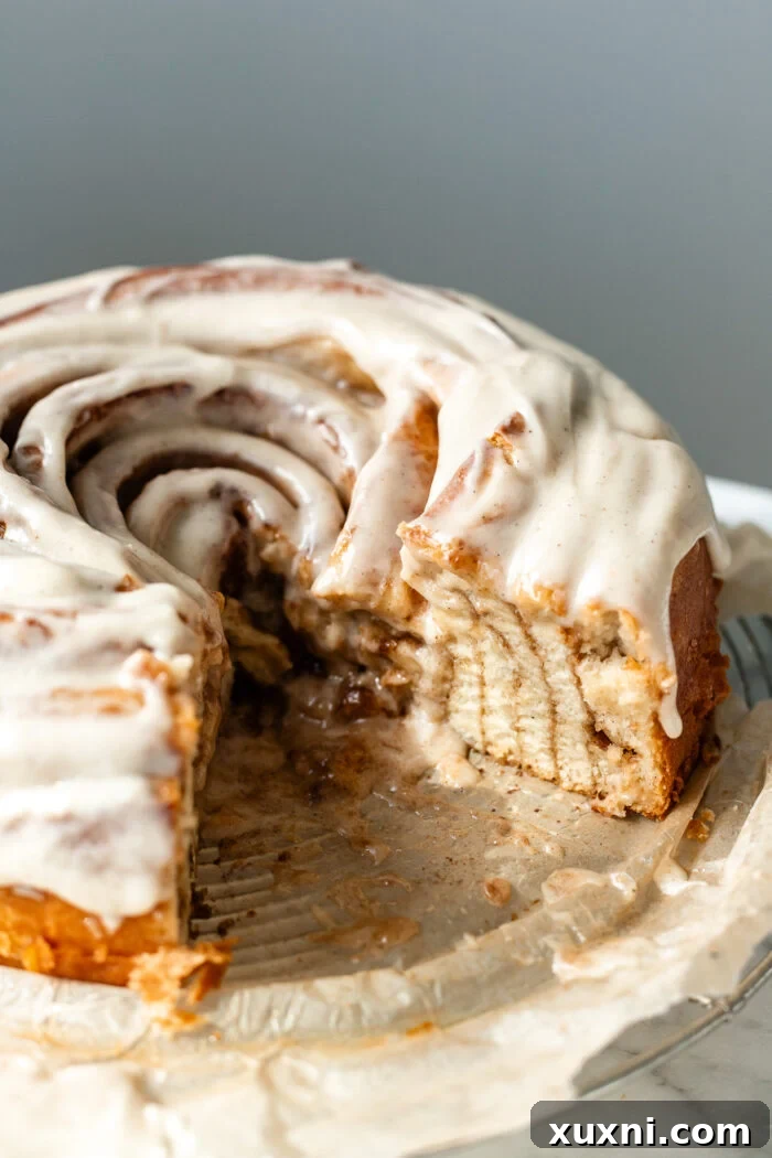 A stunning top-down view of the freshly baked and frosted giant vegan cinnamon roll cake, perfectly sliced.