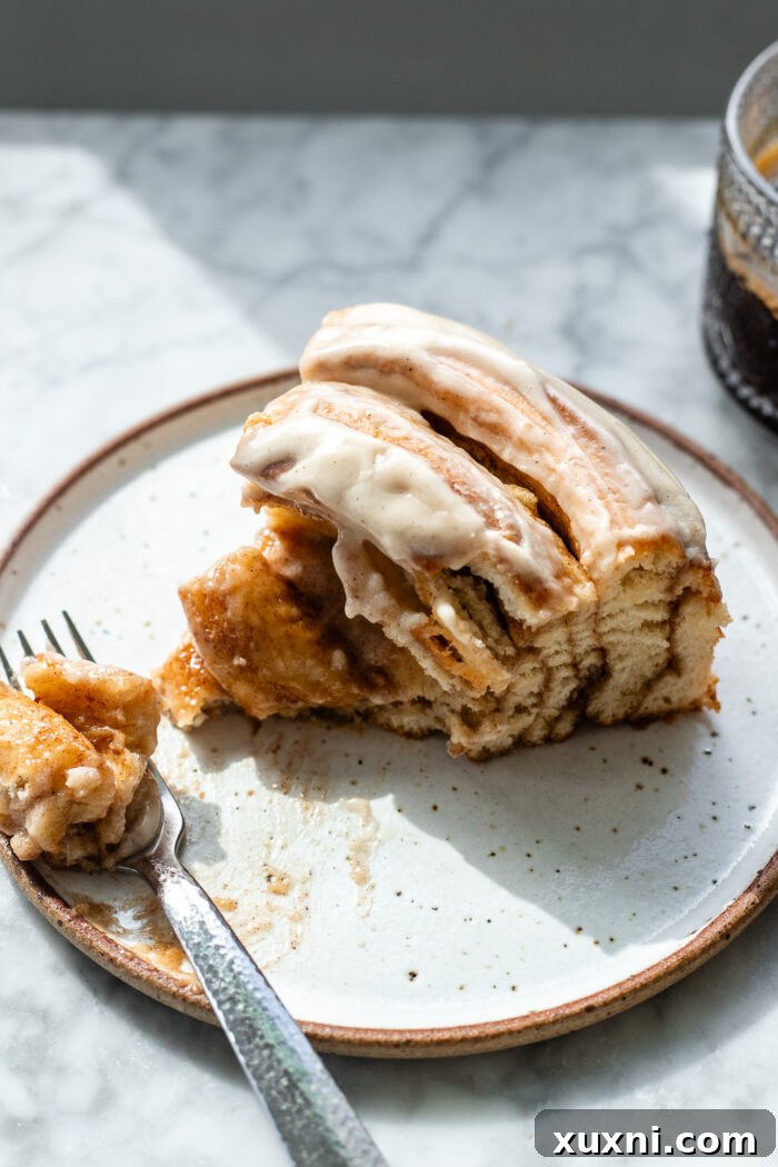 A close-up of a warm, gooey slice of the giant vegan cinnamon roll cake, showing off the rich filling.