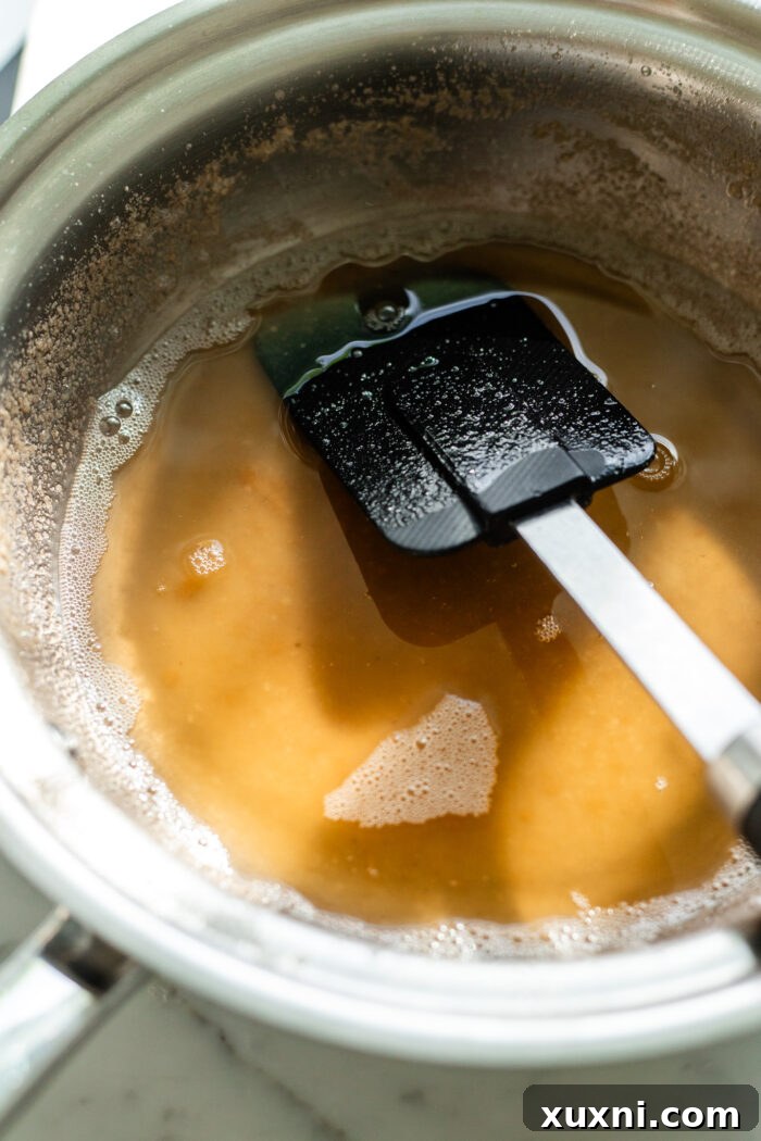 Vegan butter browning in a saucepan, showing the golden-brown flecks forming at the bottom, indicating perfect caramelization.