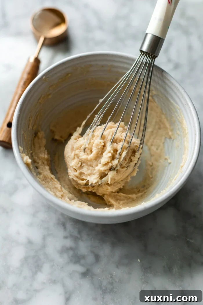 A bowl of creamy maple brown butter spread, mixed and ready to be generously applied to the cinnamon roll dough.