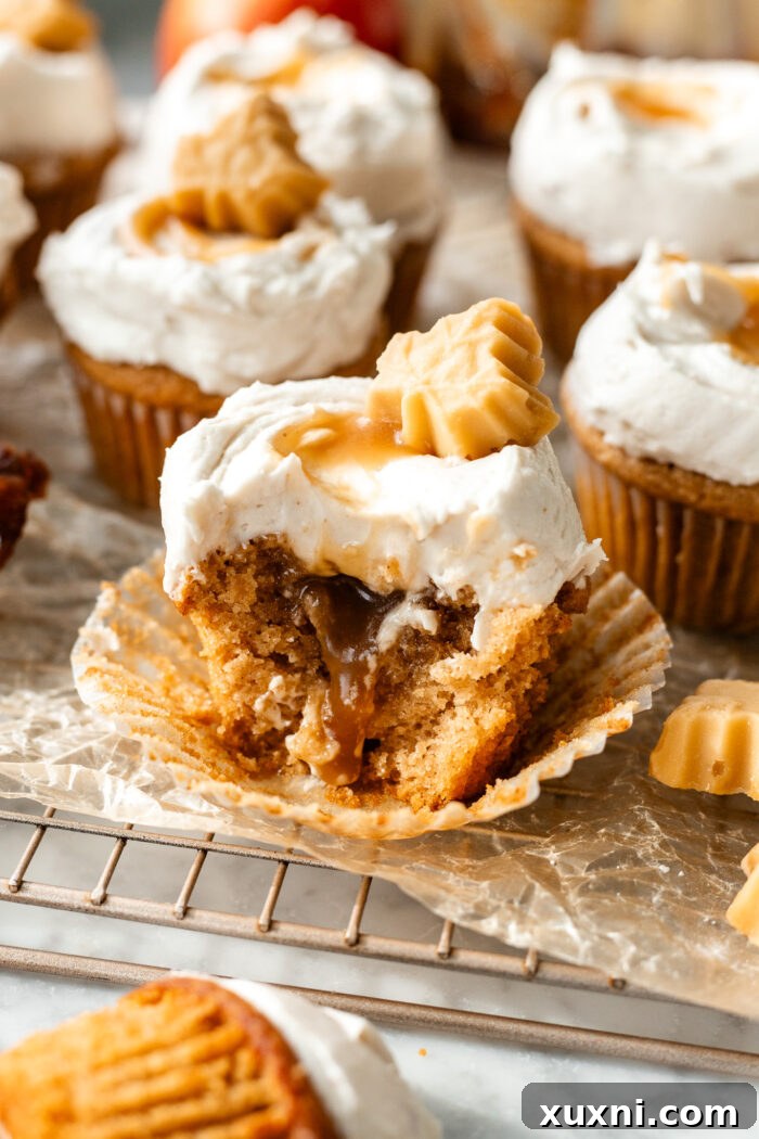 Deliciously bitten vegan apple cider cupcake revealing its salted caramel filling and brown butter cream cheese frosting.