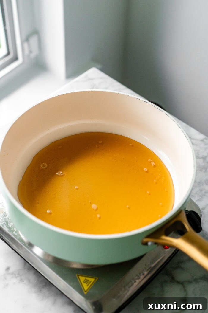 A saucepan on a stove, showing apple cider reducing to a concentrated liquid.