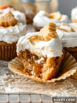 Bitten vegan apple cider cupcake showing caramel filling and frosting.