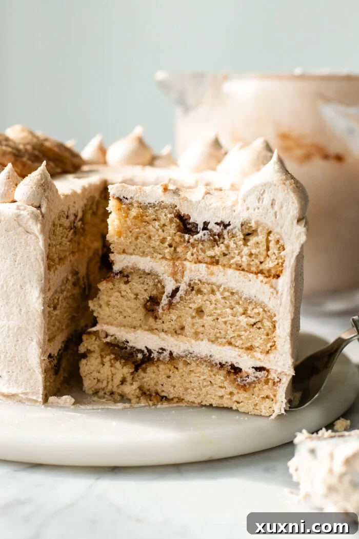 A slice of vegan snickerdoodle cake showcasing the cinnamon swirl and frosting