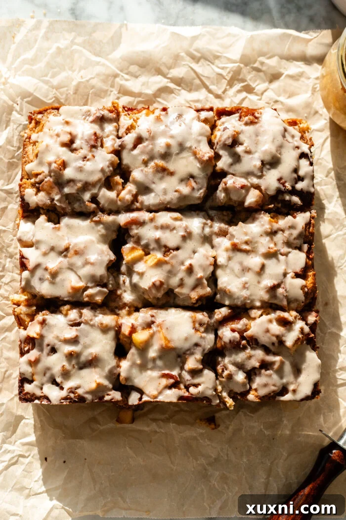Multiple slices of vegan apple fritter cake neatly arranged, showcasing the perfect crumb, apple pieces, and glaze.