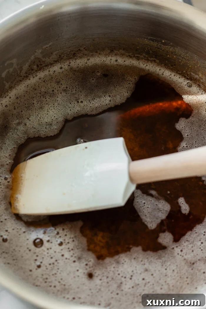 Close-up of a small saucepan containing beautifully browned vegan butter with golden flecks at the bottom, showcasing its rich, nutty transformation.