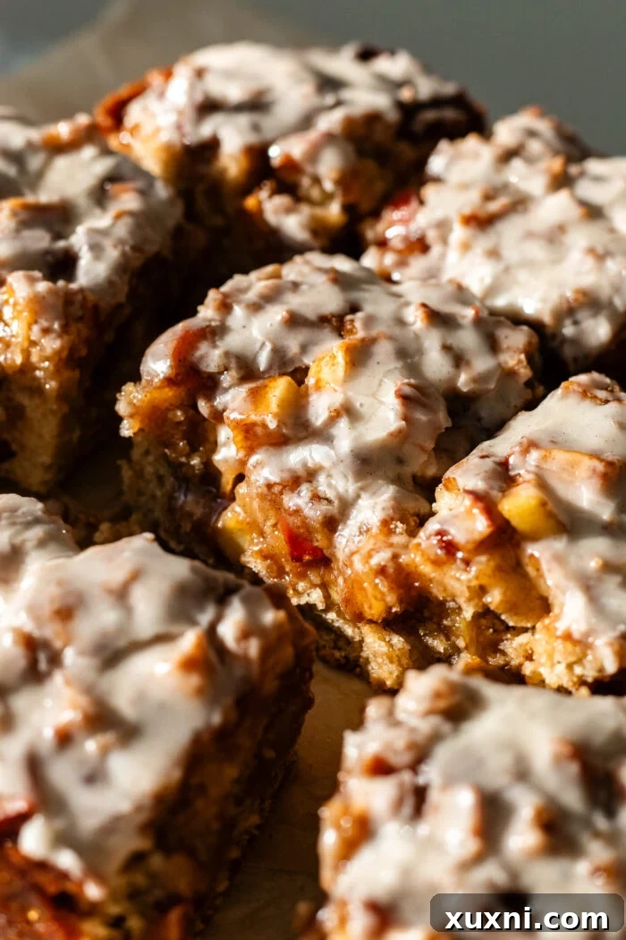 A stunning top-down view of the vegan apple fritter cake, baked in a square pan, with a delicate maple glaze drizzled generously over the cinnamon crumble and apple topping.
