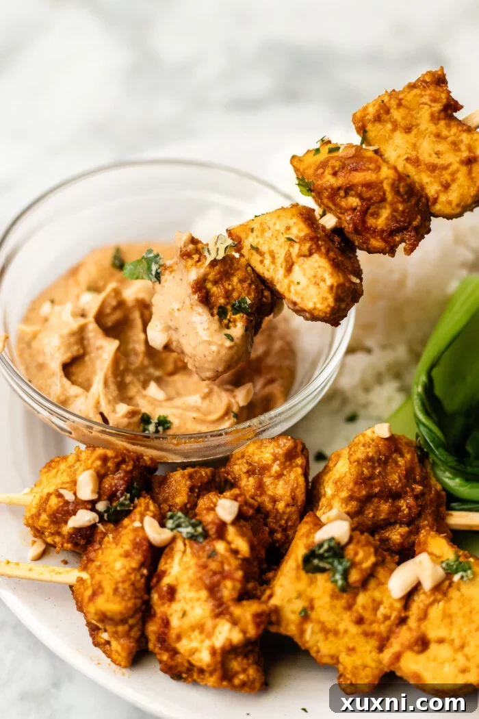 dipping the tofu satay into peanut sauce