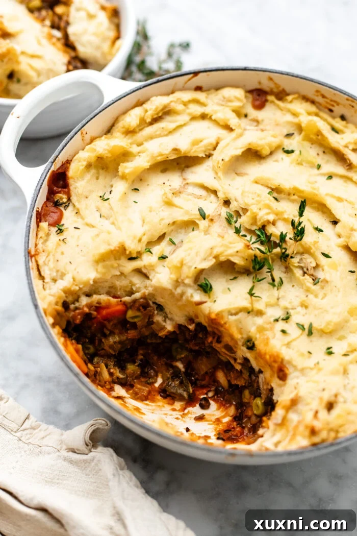 close up of vegan lentil shepherd's pie with a sprig of fresh thyme