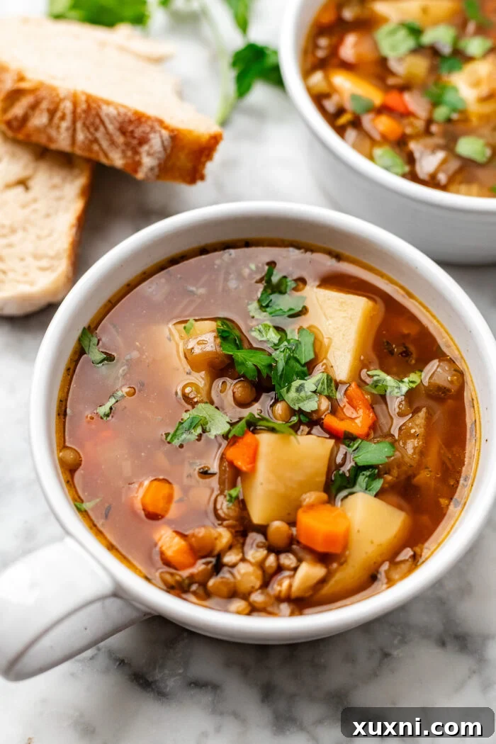 Two bowls of Brothy Lentil Potato Soup served with crusty bread on the side, ready for a cozy meal.