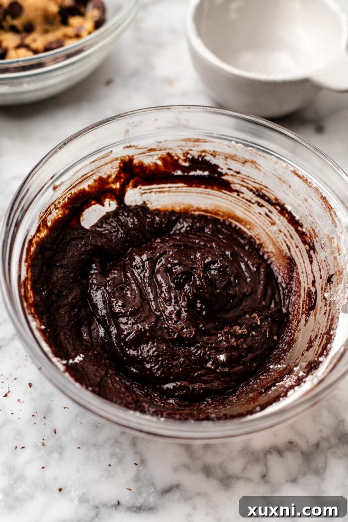 Bowl of rich, dark vegan brownie batter, smooth and ready for layering.