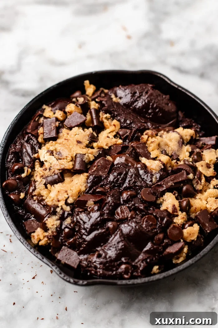 Process of assembling the mini cookie skillet, showing alternating scoops of cookie dough and brownie batter.