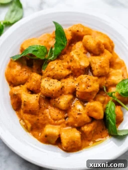 big plate of creamy roasted red pepper pasta with gnocchi and fresh basil