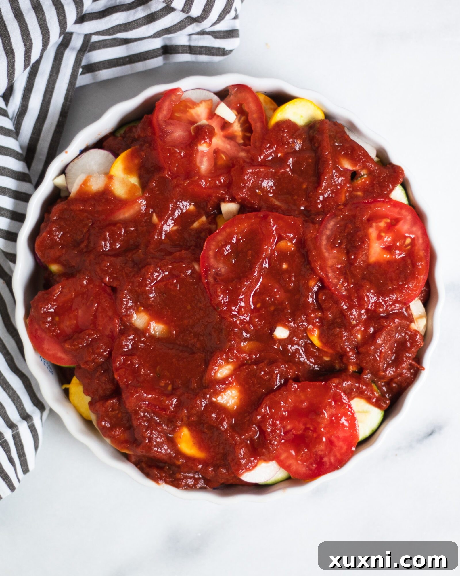 Unbaked ratatouille layered beautifully in a dish, ready to be put into the oven
