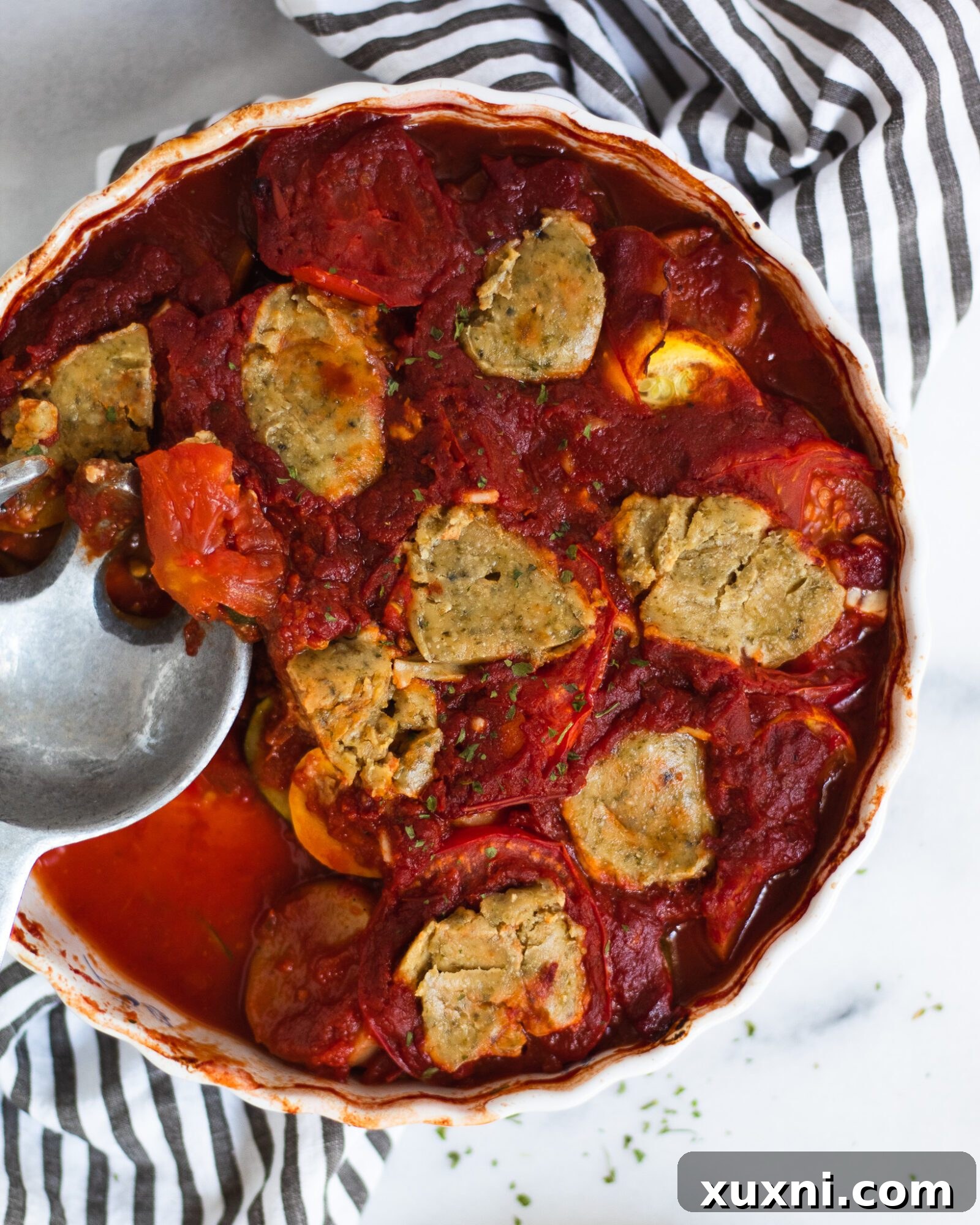 Serving spoon lifting a generous portion of baked ratatouille, highlighting its texture and freshness