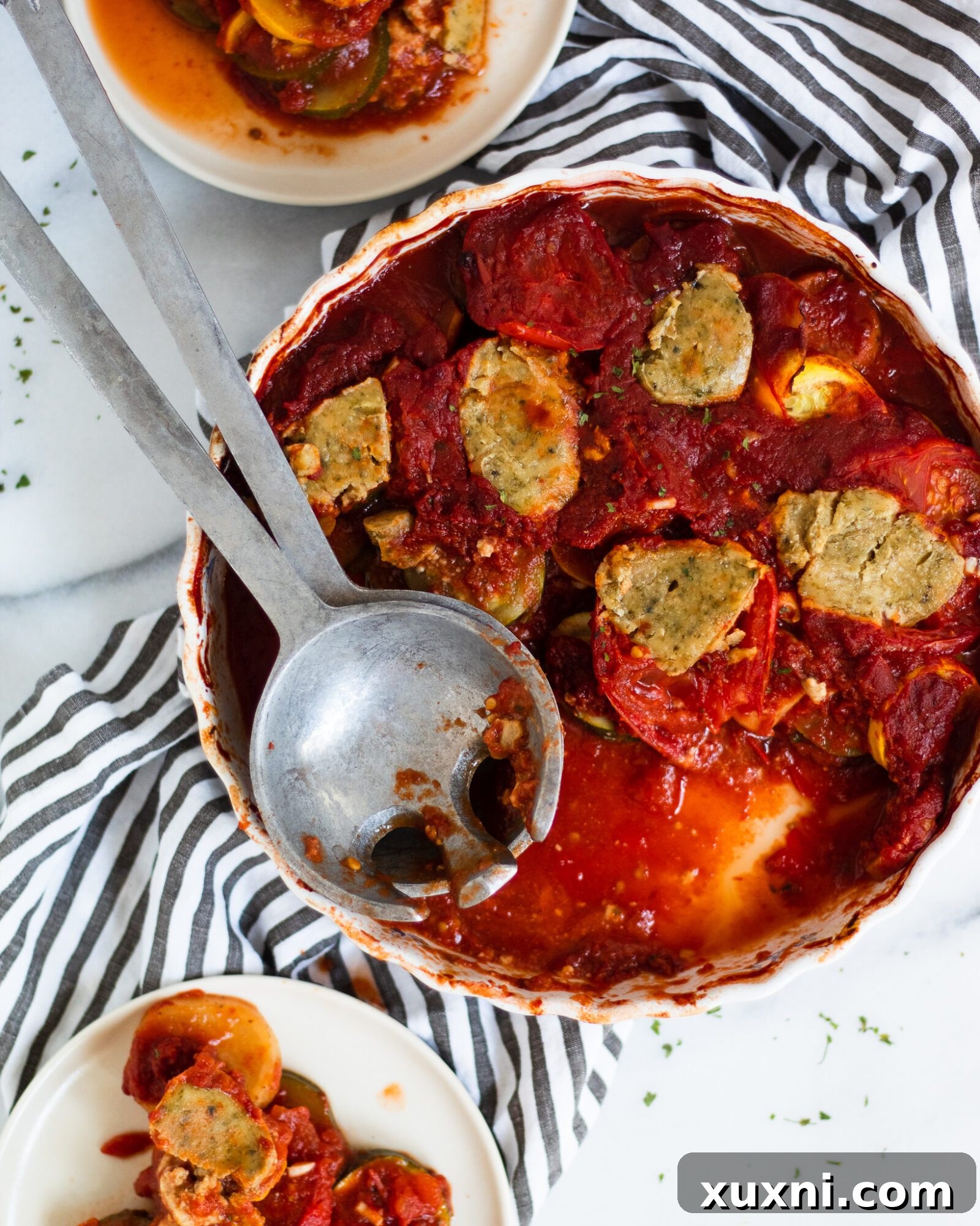 Baked tomato and zucchini dish presented with serving plates, a perfect family meal