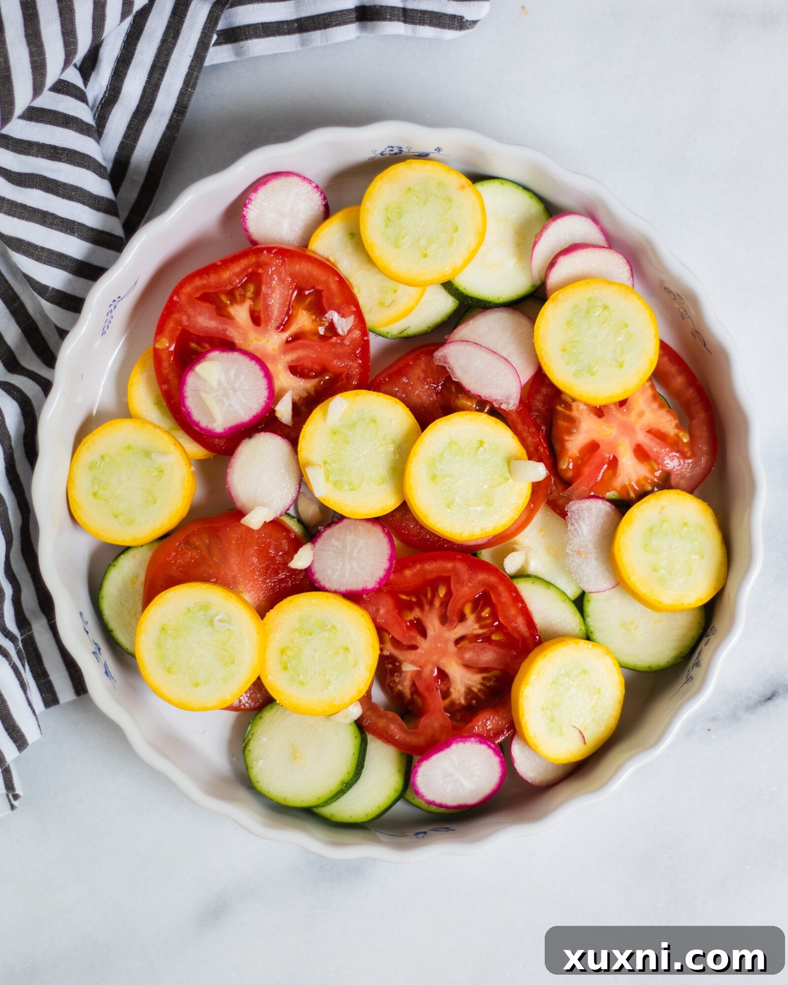 Fresh sliced zucchini and tomatoes neatly arranged in a pie dish before baking