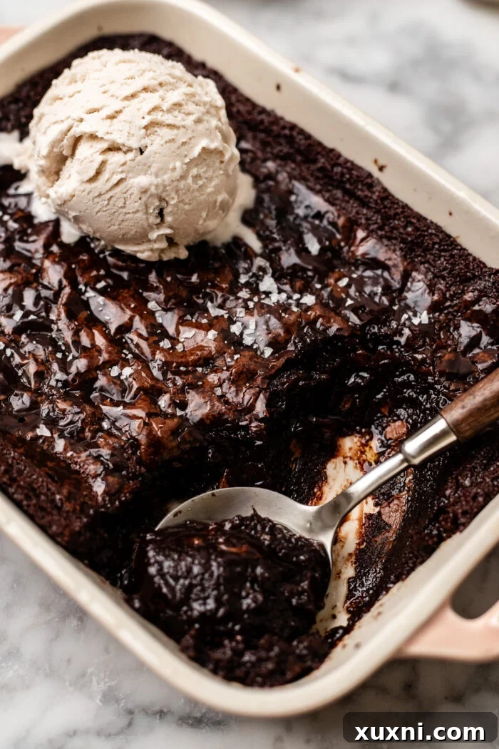 A spoon digging into the warm, gooey center of the small-batch vegan brownie pudding, showcasing its rich, molten texture.