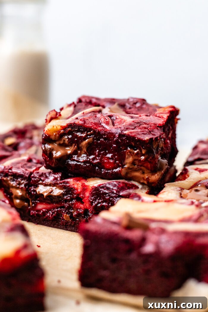 Stacked fudgy red velvet brownies, showcasing their thick, rich texture and vibrant red color.